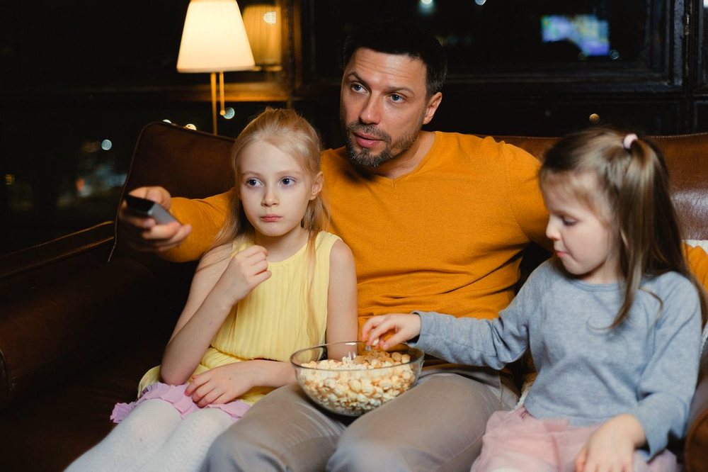 Family watching a movie together on the sofa with popcorn